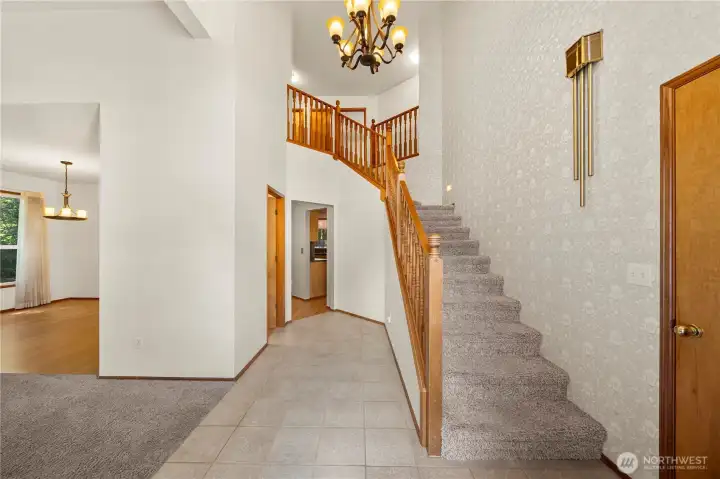 Inviting entryway with soaring ceilings and elegant staircase