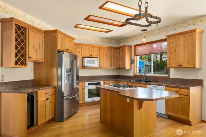 Beautiful kitchen with center island, gas cooktop, warm pine cabinetry, and abundant workspace