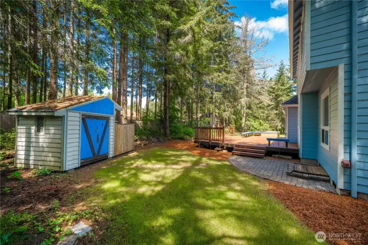 Private backyard with mature trees, storage shed, and peaceful outdoor space
