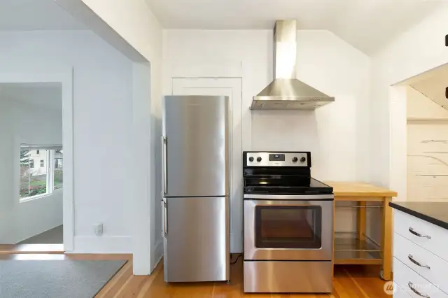 Efficient kitchen with a full-size range and stainless hood vent.