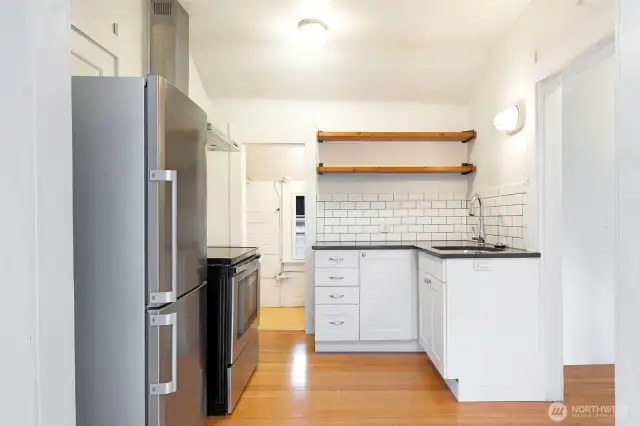 Tiled backsplash, stone counters, and floating shelves. There is also a good size pantry in the background.