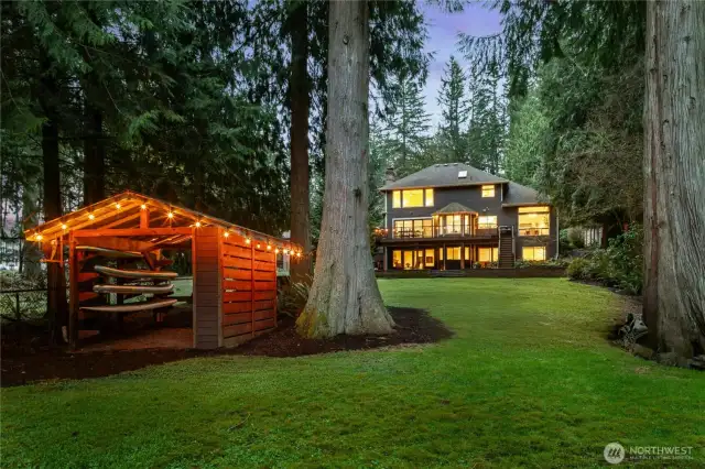 Magical evenings on the lake await! Enjoy upper and lower-level outdoor living spaces illuminated for ambiance and entertaining. Charming cedar boathouse with string lights offers easy storage for kayaks, paddleboards and all your water toys, just steps from the shoreline.