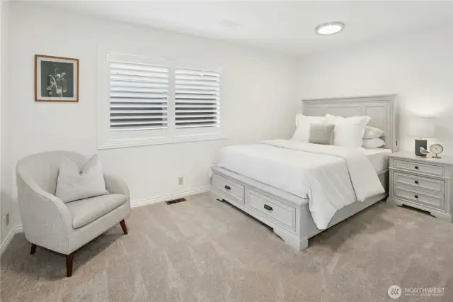 Tranquil main-level bedroom with plush carpet, plantation shutters, custom closet system and neutral tones - ideal guest space or home office in this Sammamish lakefront gem