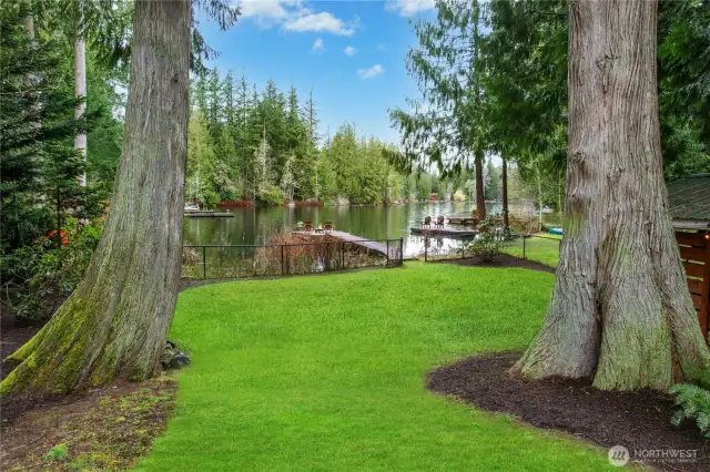 A lush, level lawn leads to the water's edge and private dock.