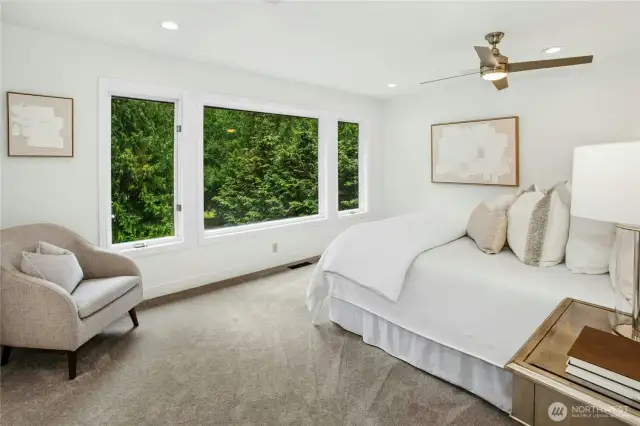 Spacious and serene primary suite with a wall of windows overlooking the water, plush carpet, generous walk-in closet, and private en-suite bath in this luxury Sammamish lakefront home.