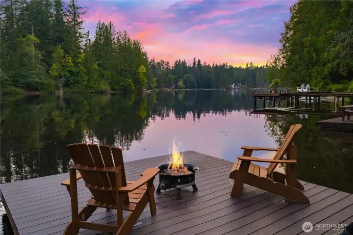 Stunning Sammamish lakefront living aglow at dusk. Evenings by the lake - unwind on your private dock as the sun sets over calm waters and a tranquil shoreline. Tour the lake and visit with friends and neighbors on your floating barge on Beaver Lake. Serene Sammamish waterfront retreat awaits with direct lake access.