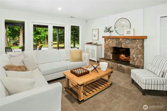 Cozy up fireside in the spacious daylight rec room, featuring a stone hearth, rustic wood mantle, and easy walk-out access to the backyard and expansive patio through French doors.