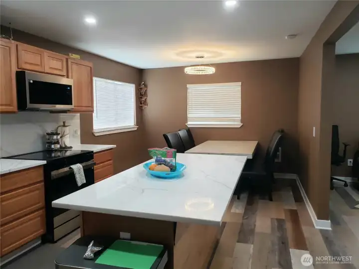 Opposite View of the Very Spacious Island Kitchen with New Granite Counter Tops, Sink, Faucet, Stainless Appliances, Real Solid Oak Cabinets, LED Lighting, Paint,Trim, and Vinyl Plan Flooring Showing Dining Room.