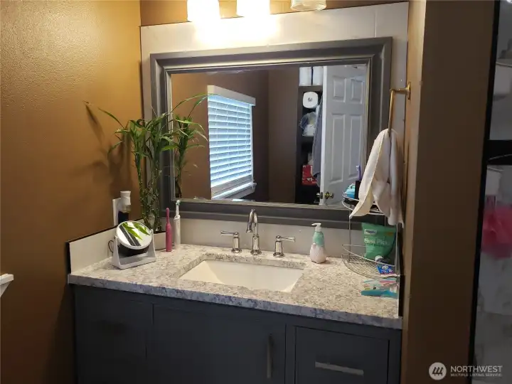 Another Close up view of the Primary Master Bath Room Showing New Vanity with Granite Counter Top, Sink, Faucet, Paint, Mirror, and Tile Flooring.
