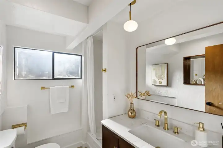 Lower level ¾ bathroom with new shower surround and fixtures, new dark wood vanity, brushed gold faucets and new faux wood mirror.