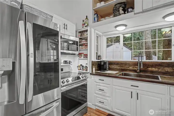 View of your kitchen and included stainless steel appliances. Storage up above is a real plus. I also love the large windows overlooking your huge wrap-around deck.