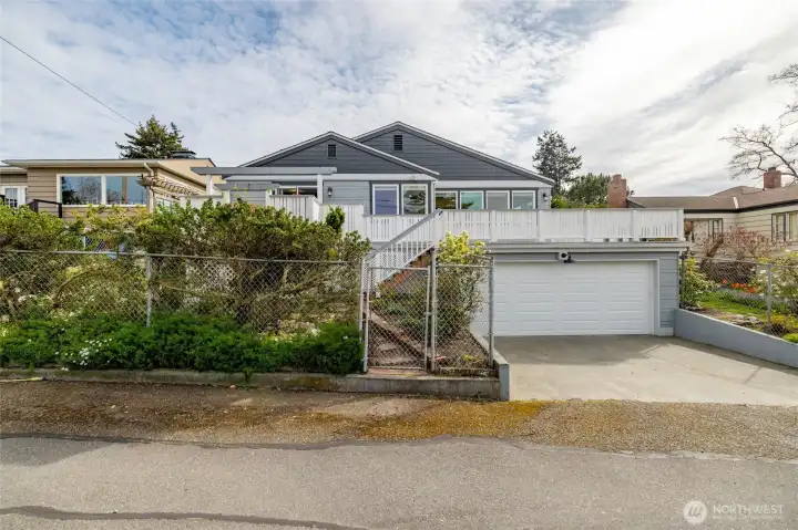 Alley view of home with the garage at left, gate into backyard and back stairs to deck in middle of photo.