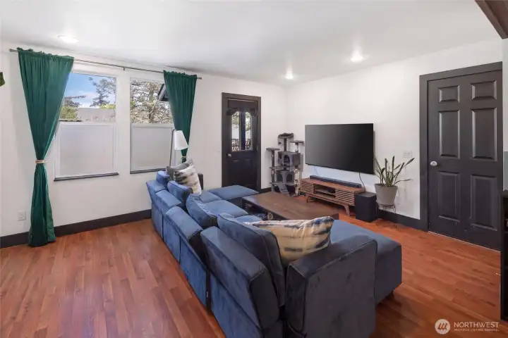 The generous living room offers a relaxed, cozy feel with plush sectional seating, recessed lighting, and large windows framing treetop views — a welcoming island retreat ready for quiet evenings or weekend gatherings.