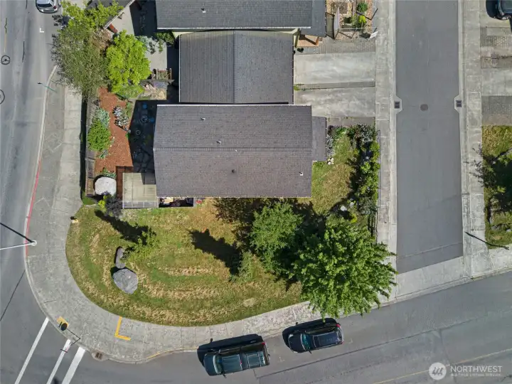 A closer overhead view showcases the thoughtfully designed private backyard sanctuary, complete with stone patio, mature plantings, and a pergola — rare outdoor living space for an in-town island property. The attached garage and clean rooflines reflect quality construction in a coveted walkable location.
