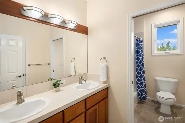 Full bath with dual vanities off the hallway.