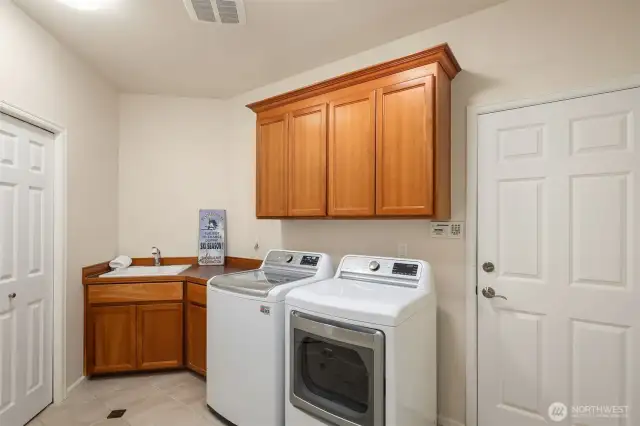 Laundry room with utility sink & handy storage cabinets.