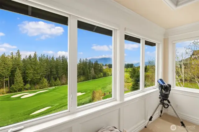 Wrap-around view windows overlook the green fairways & mountains beyond.