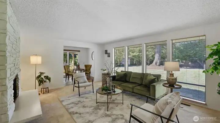 Relax in this sun-filled living room framed by walls of windows overlooking the lush backyard.