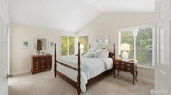 Beautiful double doors open to the spacious primary suite.  A peaked ceiling amplifies the natural light that pours from the large windows.