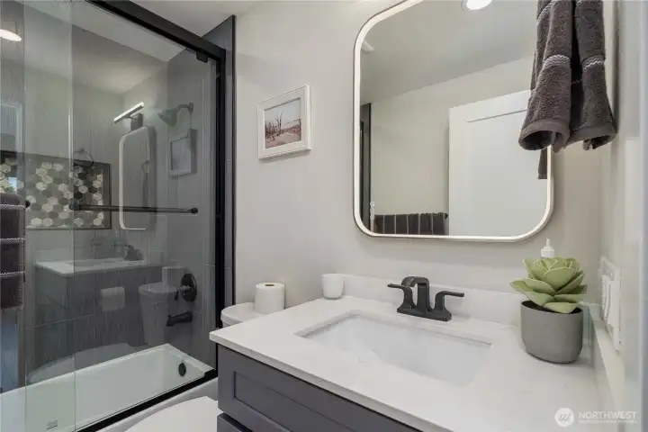 Main hall bath with custom tiled shower, river rock cubby, smart mirror