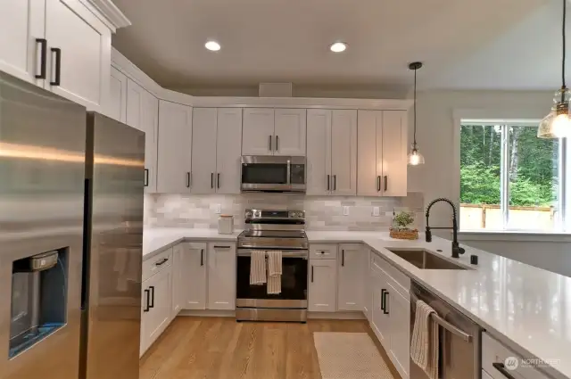 Designer kitchen with stainless appliances and quartz countertops.