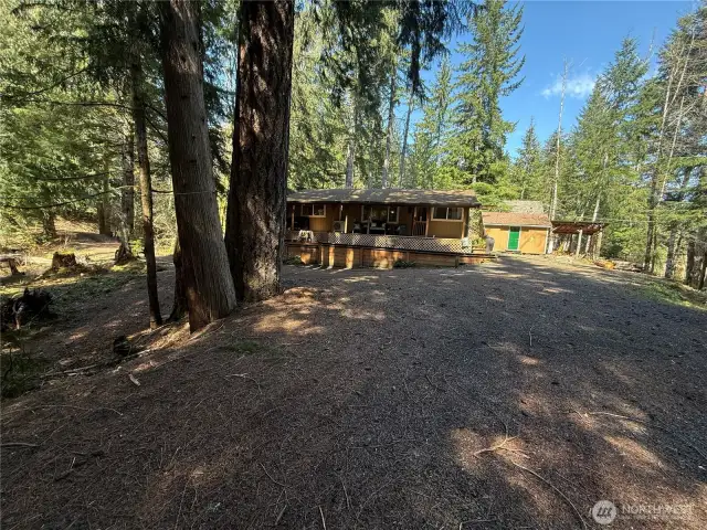 Great view of cabin, large deck and oversized shed and wood shed.