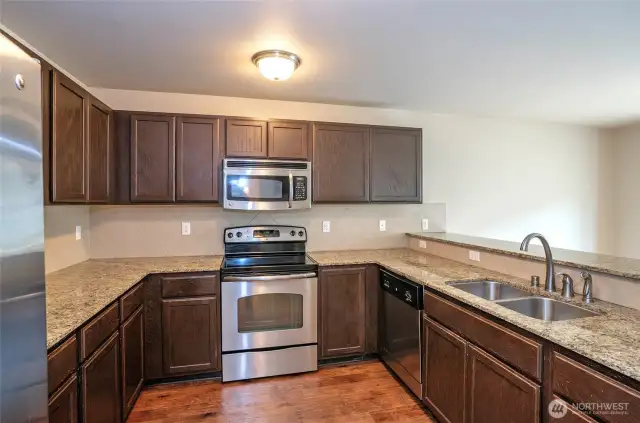This well-designed kitchen offers plenty of room for cooking, with sleek solid countertops and rich cabinetry.