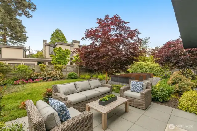 Fully fenced front yard with paver patio and custom built steel raised flower beds.