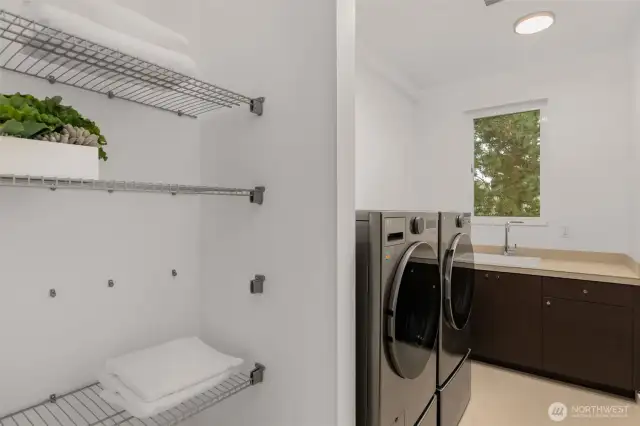 Convenient upper laundry room with New LG High Capacity washer and dryer, laundry sink, and optimal storage.