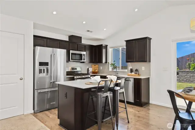 Kitchen sink overlooks the backyard.  The Kitchen features Quartz slab counter tops, tile backsplash and stainless steel appliances.   seating at the kitchen island is perfect for company while you cooke or a quick snack.