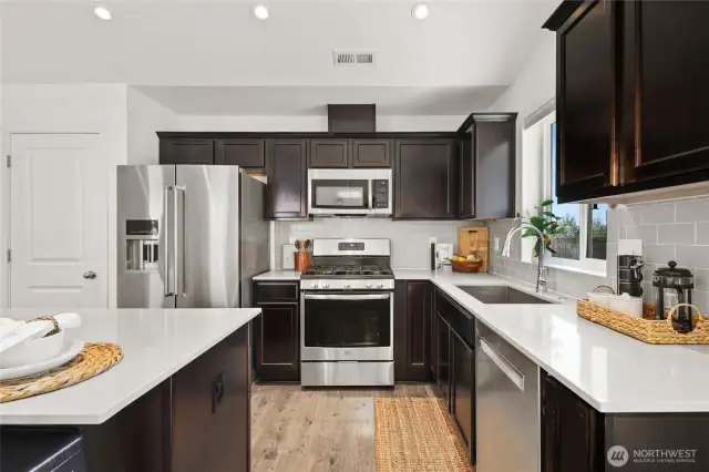 Kitchen features Quartz slab counter tops, tile backsplash and stainless steel appliances