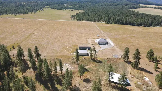 Aerial view. Deer-fenced garden has large green house and raised beds. Areas around the home have underground sprinkler systems that are set up on a timer.