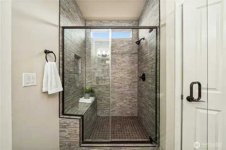 Fully tiled shower with a bench and a niche.