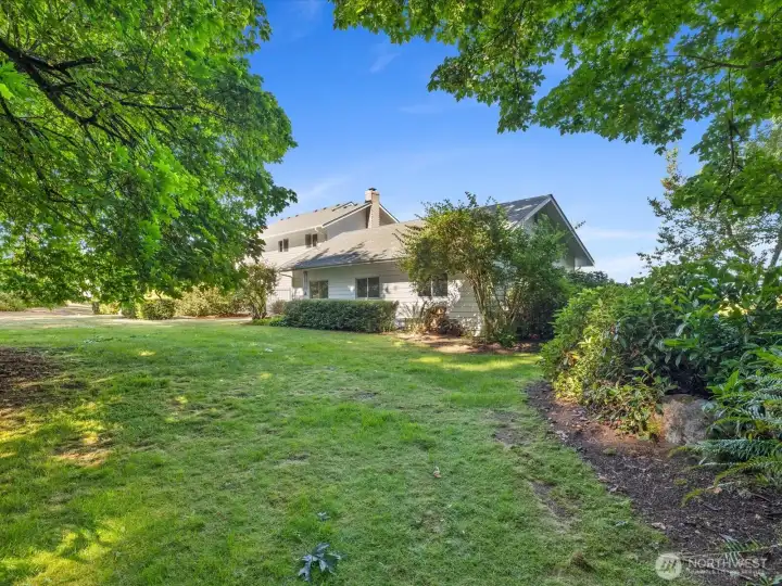 Beautiful sprawling yards create outstanding outdoor spaces, with    mature trees, many blooming flowers, & large wooded area.