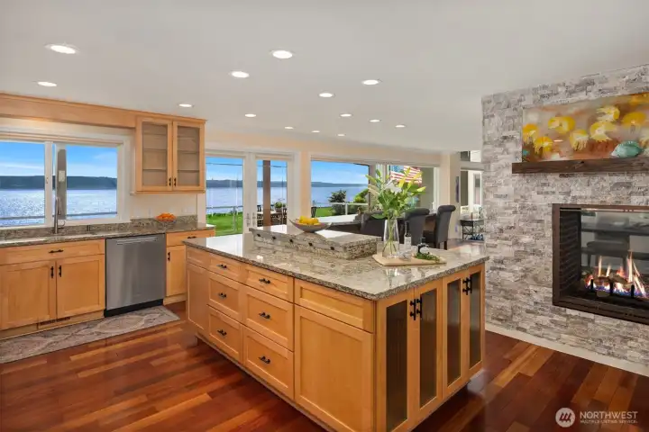 The chef’s kitchen is truly spoiled, featuring stunning water views and a dramatic double-sided fireplace that adds warmth and ambiance to both the kitchen and living spaces.
