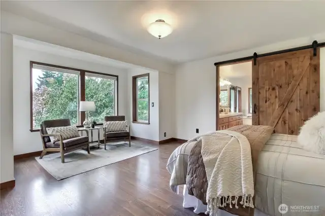 Primary bedroom has wraparound deck access and space for a sitting area near the windows.