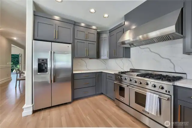 There is plenty of space to entertain in this large, updated kitchen that feature new cabinetry, quartz countertops and backsplash, refinished hardwood floors, 48" gas stove, and updated light fixtures.