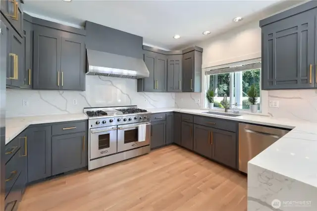 There is plenty of space to entertain in this large, updated kitchen that feature new cabinetry, quartz countertops and backsplash, refinished hardwood floors, 48" gas stove, and updated light fixtures.