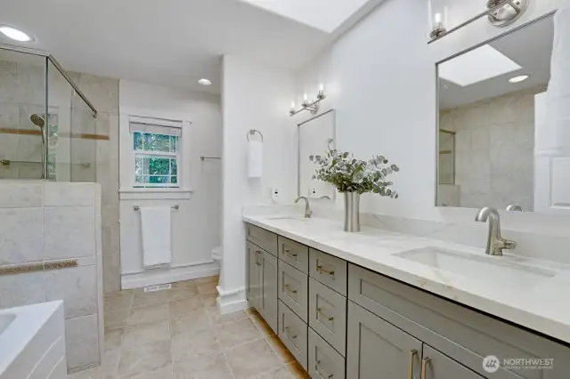 The primary en-suite features a large, new vanity with slab countertop, new mirrors and light fixtures, tiled shower and jetted tub.