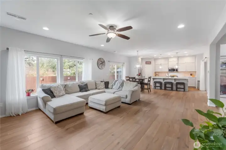 A wider look at the main living space, showcasing the seamless transition from the living room to the kitchen and dining nook. Multiple windows brighten the entire area and create a welcoming, open environment perfect for everyday living and entertaining.