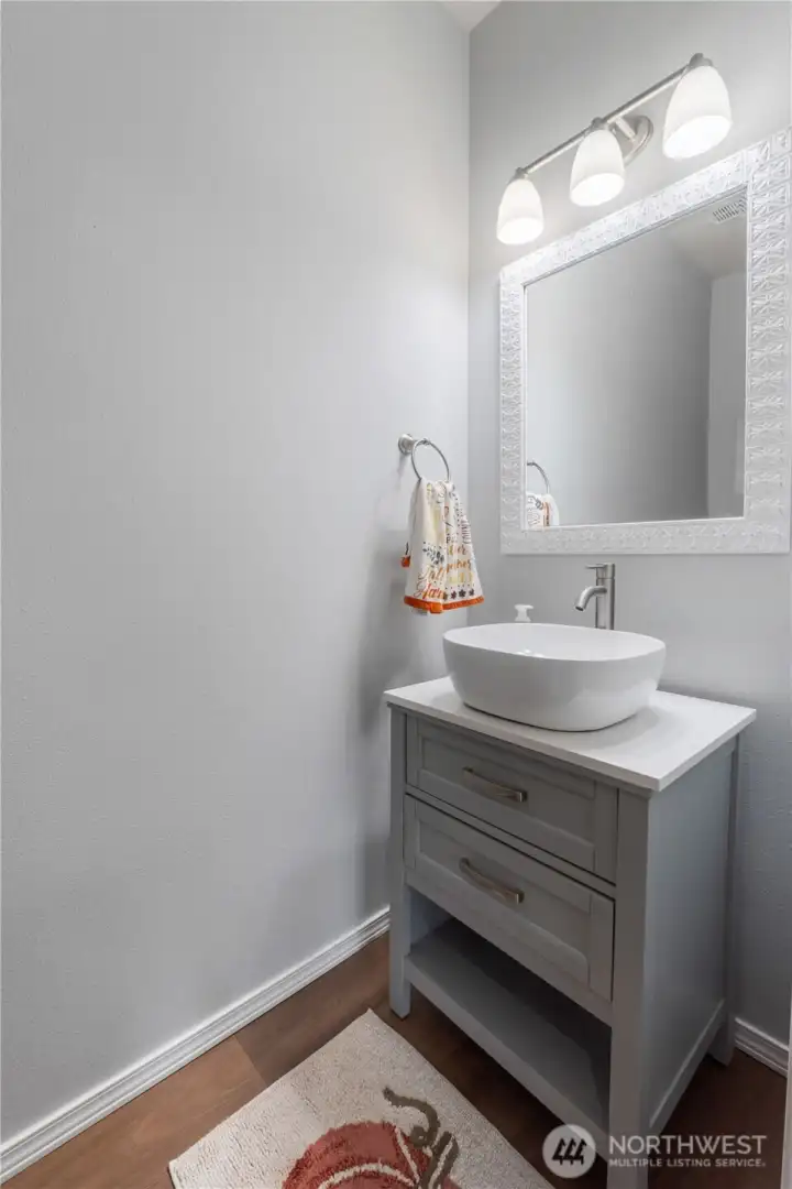 A stylish main-level powder room with a modern vessel sink, updated vanity, and bright lighting. Simple finishes create a clean, welcoming space for guests.