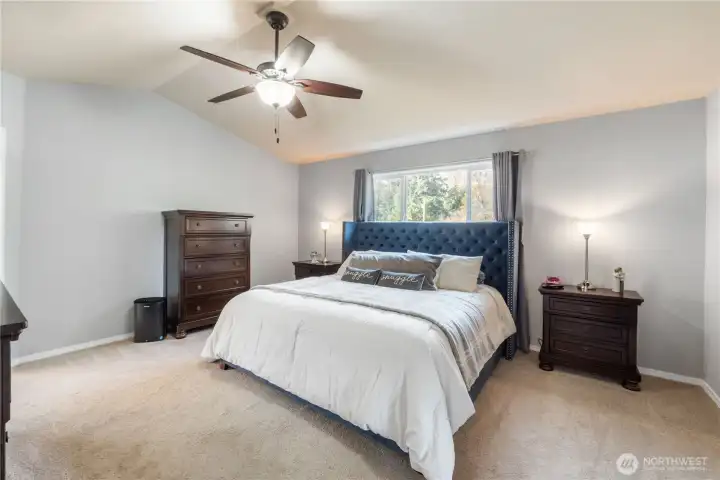 A spacious primary bedroom with vaulted ceilings and a large window overlooking the peaceful backyard. The room easily accommodates a king-sized bed with room to spare for additional furniture. A relaxing, private retreat at the end of the day. Ceiling Fans in all bedrooms.