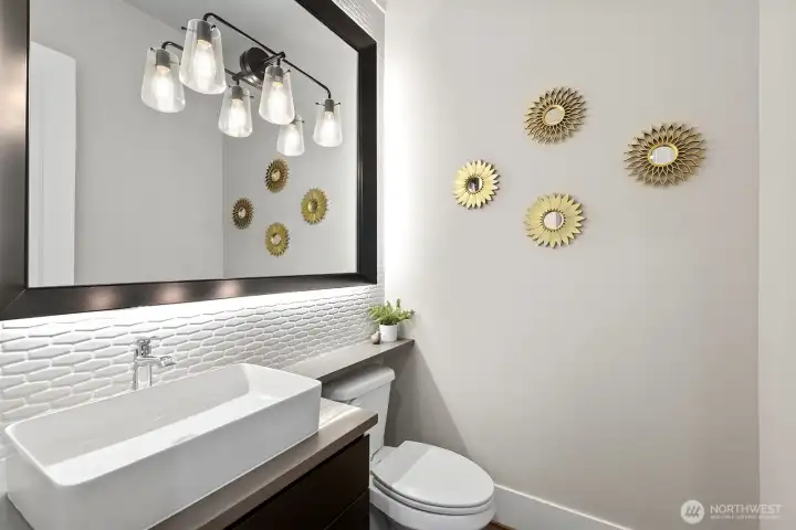 Beautiful powder room on main level with custom mirror surround , back splash and accent lighting.