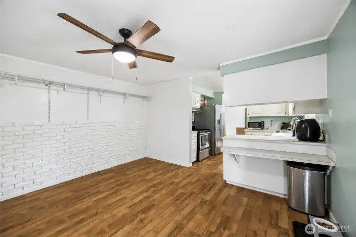 Second living room with a fun brick accent wall and a ceiling fan. Cute little bar off of the kitchen could make a great homework or crafting spot.