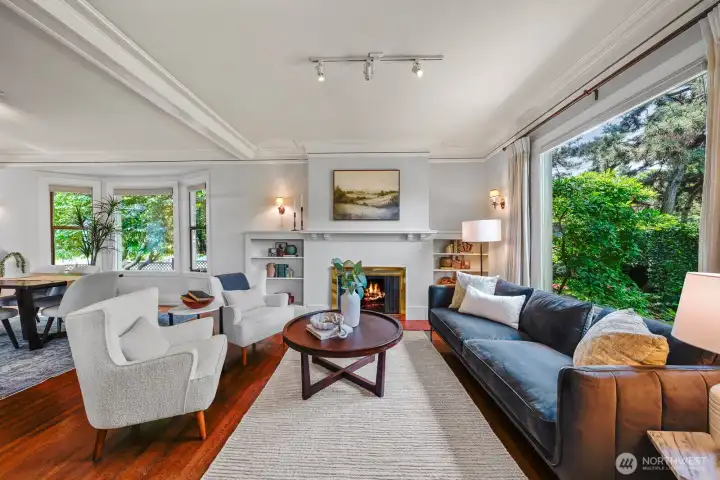 This sun-filled living area is anchored around a  wood-burning fireplace and flows effortlessly into the adjacent dining room. Expansive windows provide peaceful views of the stunning manicured grounds.