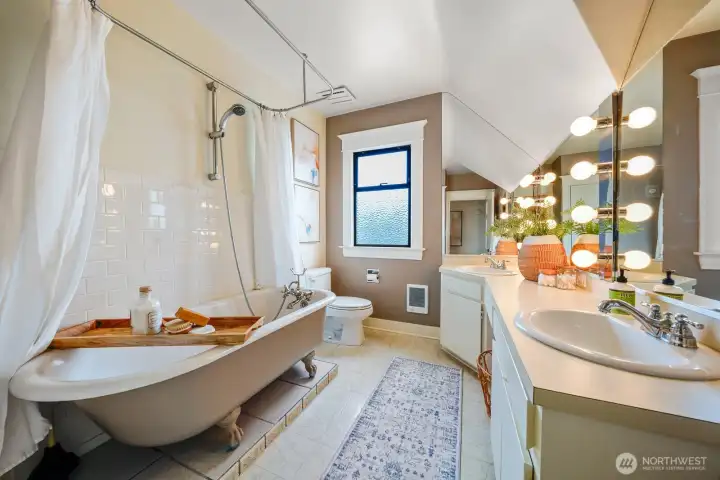 Glam overload! This bathroom defines style with its stunning clawfoot tub, double sinks, and Hollywood mirror lighting.
