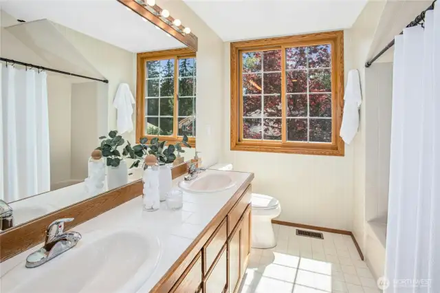 The upstairs hall bathroom features dual sinks, tiled shower/tub, and cabinet storage.