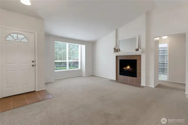 warm and inviting entry view featuring vaulted ceilings, a charging bump-out window that brings in natural light, and a cozy gas fireplace