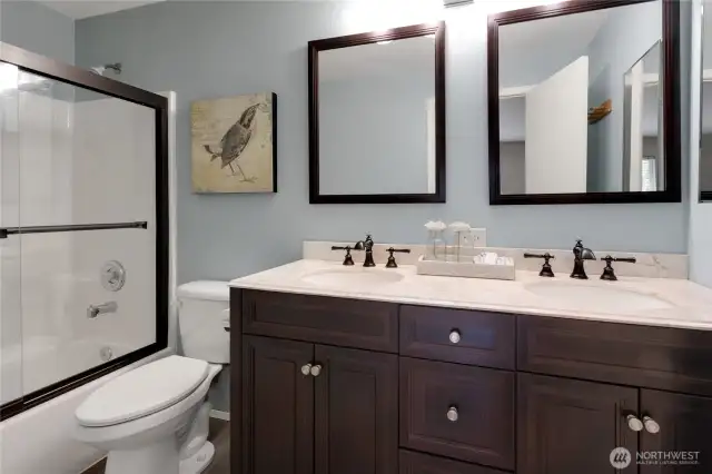 Spacious primary bathroom featuring a double vanity with dual sinks, a full tub and shower combo, and durable new vinyl plank flooring.