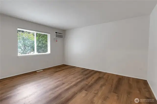 Primary suite featuring wall-mounted AC unit, new wood laminate flooring and spacious wall to wall closet.  With the convenience of an attached private bathroom.